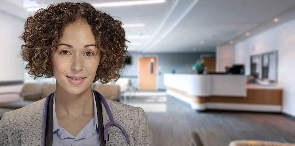 hcp-with-clinic-in-background Health Care Professional standing in modern clinic